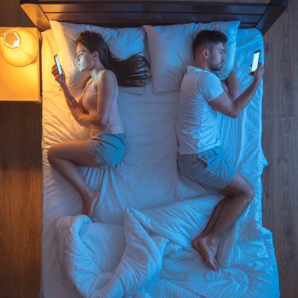 Paar mit dem rücken zueinander die im bett liegen und im handy schauen